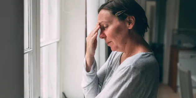 Väsynyt nainen hieroo sormilla otsaansa. Silmät ovat kiinni. Tuoreen väitöskirjan mukaan hoitotyöntekijöiden haitallisen päihteiden käytön ehkäisyä ja varhaista puuttumista on tutkittu vähän.