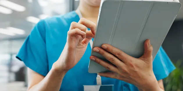 Hoitaja kirjaamassa tai katselemassa tietoja tabletilla.