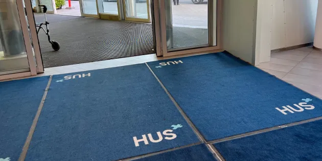 Kuvassa Husin ulko-oven seutua, jossa on useampi sininen kynnysmatto.