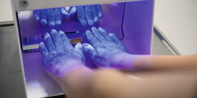 Hoitaja on laittanut kätensä laitteeseen, joka tarkastaa, onko kädet pesty kunnolla.