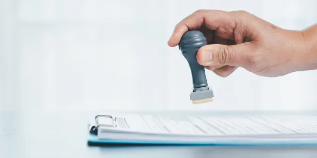 Käsi leimaamassa paperipinoa.