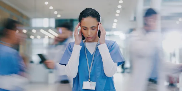 Sairaanhoitaja hälinää täynnä olevassa työympäristössä. 