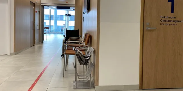 Sairaalan tyhjä käytävä. Seinustalla tuoleja. 