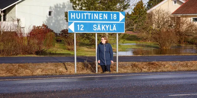 Esihenkilö Minna Kyttänen seisoo tien pientareella. Tienviitoissa lukee "Huittinen 18" ja "Säkylä 12".
