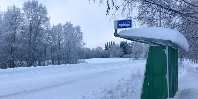 Linja-autopysäkki syrjäseudulla keskellä talvista lumimaisemaa.