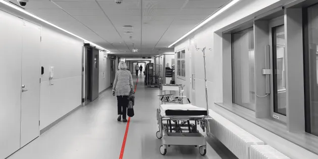 Vanus kävelee sairaalan pitkää käytävää poispäin kamerasta.