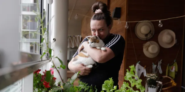 Lähihoitaja Kiia Malin Miiru-kissa sylissään Kontulan seniorikeskuksen parvekkeella.