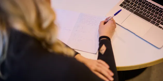 Nainen laskee laskuja paperille. 