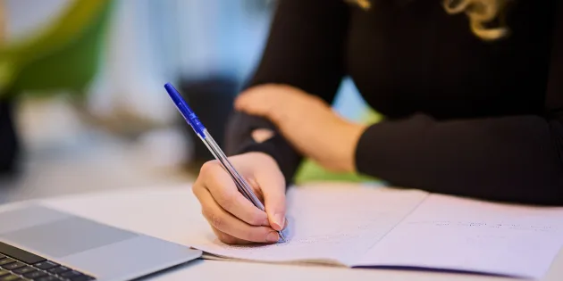 Ihminen laskee kynällä paperille.