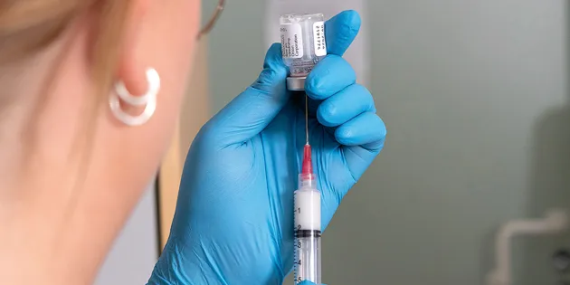 Sairaanhoitaja laittaa lääkettä ruiskuun.