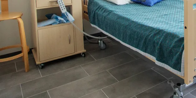 Palvelukodin huone, jossa sairaalavuode, yöpöytä ja tuoli.