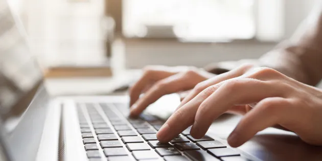 Henkilö kirjoittamassa someen tekstiä kannettavalla tietokoneella.