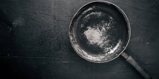 Vanha ja kulunut paistinpannu tumman pinnan päällä.