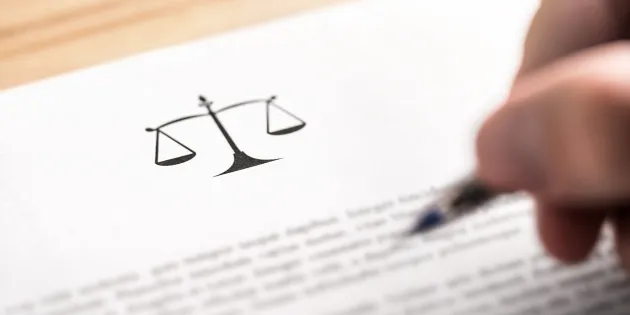 Tuntematon hahmo lukee lakitekstiä kynä kädessä.