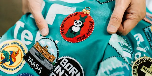 Opiskelija pitää haalaria käsissään ja näyttää siinä olevia haalarimerkkejä.