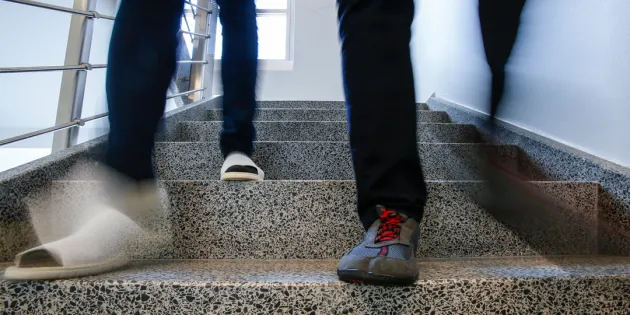 Kuvassa kahden henkilön jalat, jotka laskeutuvat alas rappusia.