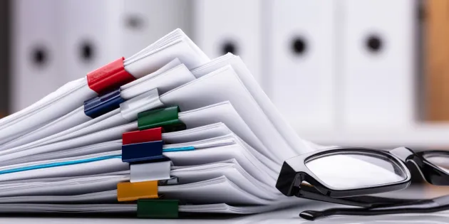 Sopimuspapereita pöydällä.Silmälasit paperipinon vieressä.