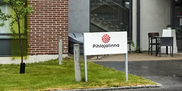 Pihlajalinnan logo kyltissä rakennuksen pihalla.