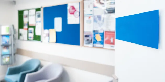 Kuva odotustilassa, jossa juoma-automaatti, tuoleja ja lappuja ilmoitustaululla.