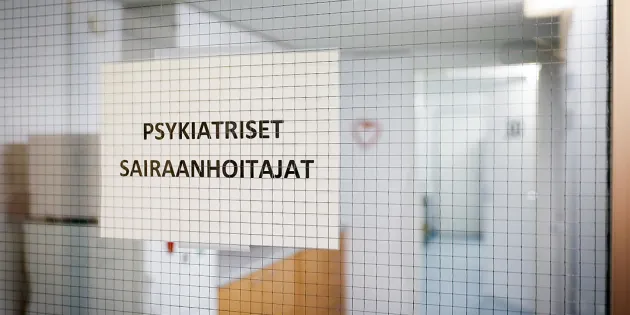 Kuva sairaalan käytävästä, jossa kiinni oleva lasiovi ja siinä tulostettu lappu tekstillä &quot;psykiatriset sairaanhoitajat&quot;.