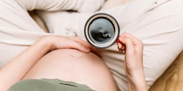 Raskaana oleva nainen juomassa kahvia kupista. Yksi kuppi kahvia riittää väitöksen mukaan raskaana olevalle.