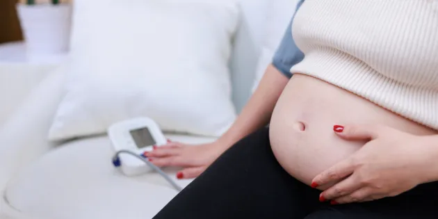 Raskaana oleva nainen mittaa verenpainettaan.