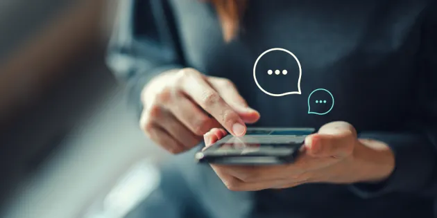 Henkilö pitää puhelinta kädessä ja kirjoittaa chat-tukeen viestiä.