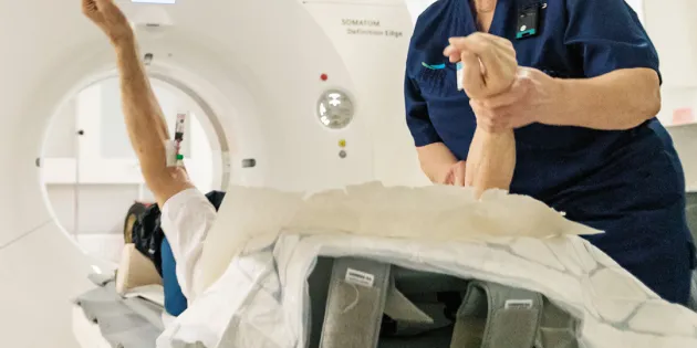 Röntgenhoitaja avustaa potilasta kuvauksessa.