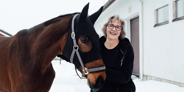 Kirsi Nicklén seisoo hevosen vierellä ulkona.