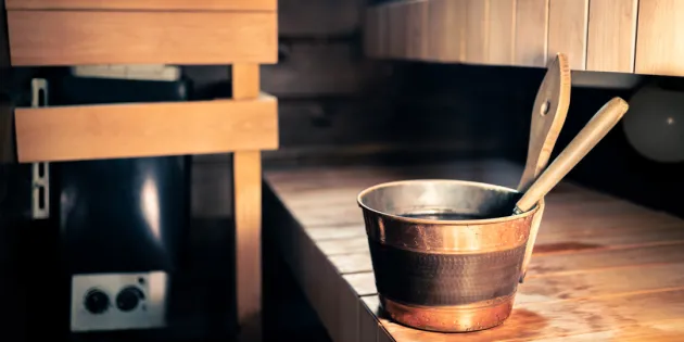 Saunan laiteilla löylykaukalo. Taustalla näkyy kiuas.