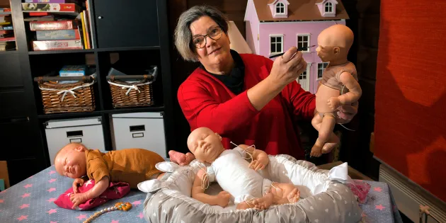 Sairaanhoitaja Marjut Sarka ja kolme reborn-nukkea.