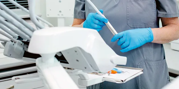 Suuhygienisti työvälineidensä äärellä suojahansikkaat kädessä.