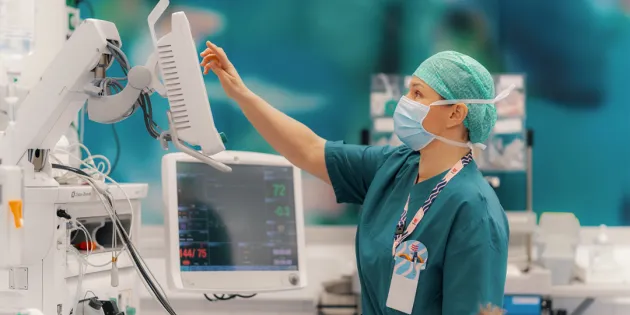 Hoitaja käy läpi leikkaussalin laitteita.