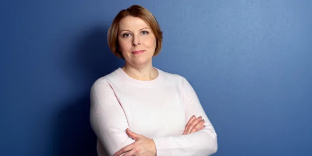 Tehyn toiminnanjohtaja sekä edunvalvontajohtaja Else-Mai Kirvesniemi katsoo hymyillen kameraan sinistä taustaa vasten.