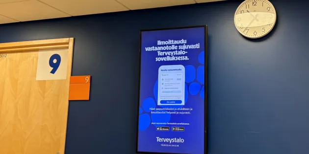 Terveystalo aloittaa uudet, entistä isommat muutosneuvottelut. Terveystalon seinällä sähköinen mainostaulo Terveystalon omasta sovelluksesta.