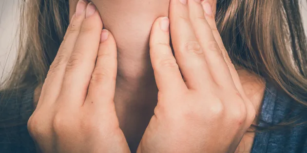 Nainen pitelee kaulaansa.