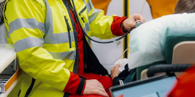 Ensihoitaja tarkkailee potilasta ambulanssissa.