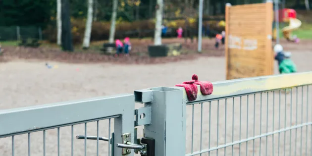 Syksyinen päiväkodin piha ja portti ja aita.