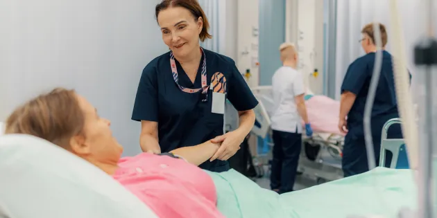 Keski-ikäinen hoitaja työssään sairaalassa auttaa potilasta – hyvät työolot ja terveystottumukset tukevat ikääntyvien työntekijöiden työkykyä ja jaksamista.