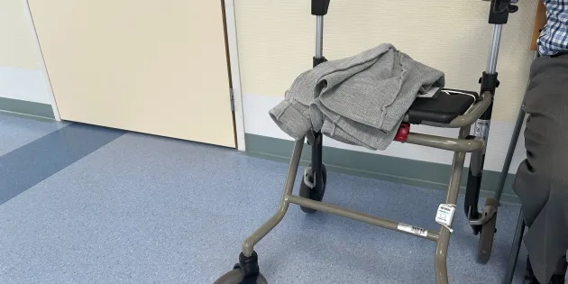 vanhus istuu käytävällä vieressään rollaattori.