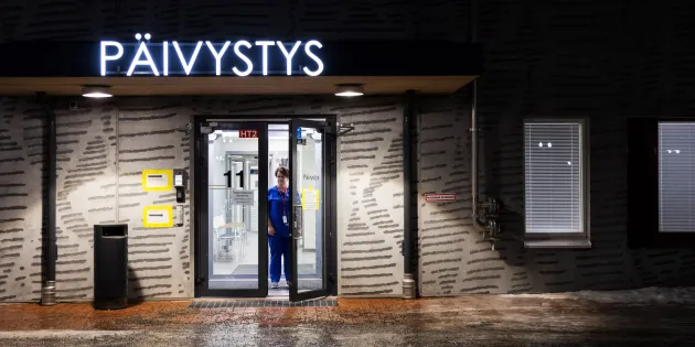 Varkauden perusterveydenhuollon yöpäivystys kuvattuna yöllä. Hoitaja seisoo ovella.