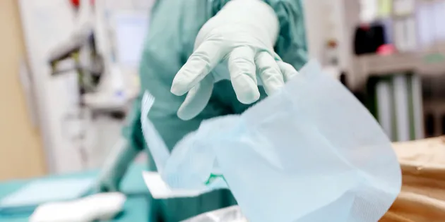 Käsi, jossa hansikas heittää roskan roskikseen.