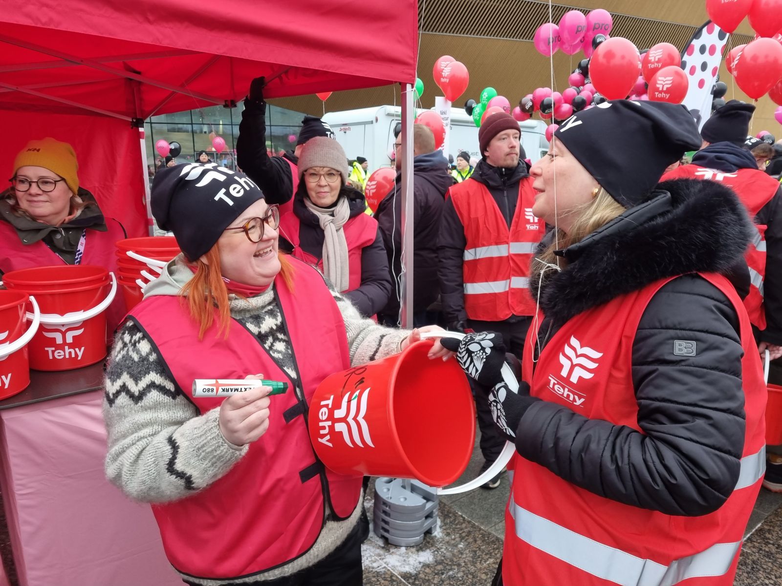 Millariikka Rytkönen kirjoittaa nimikirjoitusta ämpäriin mielenosoituksessa.