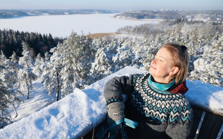 Vivi Aaltonen nautiskelee lumisessa maisemassa näköalapaikalla.