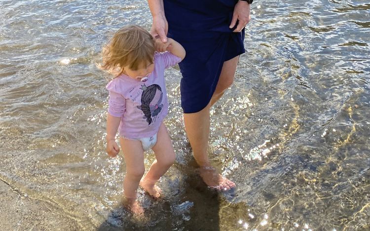 Niina kävelee tyttärentytär Emilien kanssa rantavedessä.