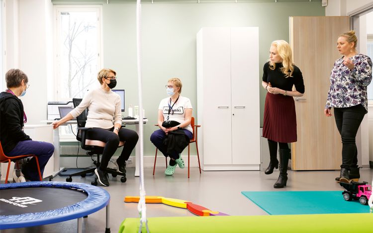 Viisi perhekeskuksen työntekijää on kokoontunut samaan huoneeseen.