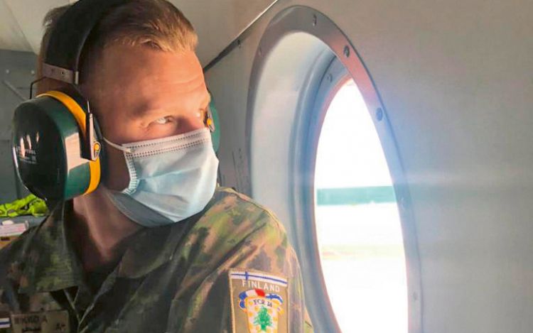 Mikko Alamäki katsoo ulos helikopterin ikkunasta maski kasvoillaan.