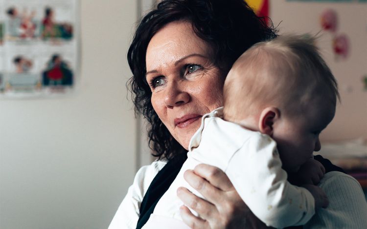 Terveydenhoitaja Inkeri Jussila pitää sylissään pientä vauvaa.