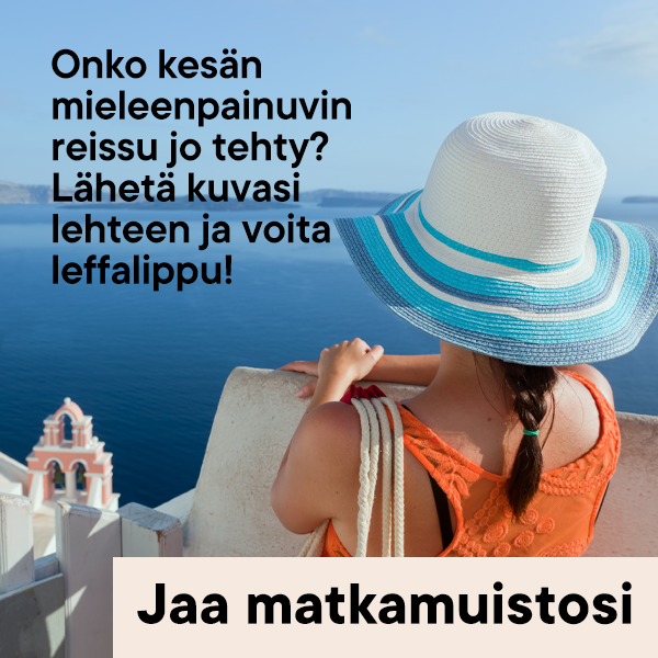 Nainen kesähatussa seisoo selin kameraan Kreikan meren edustalla. Taustalla näkyy Santorinin talojen kupoleita.