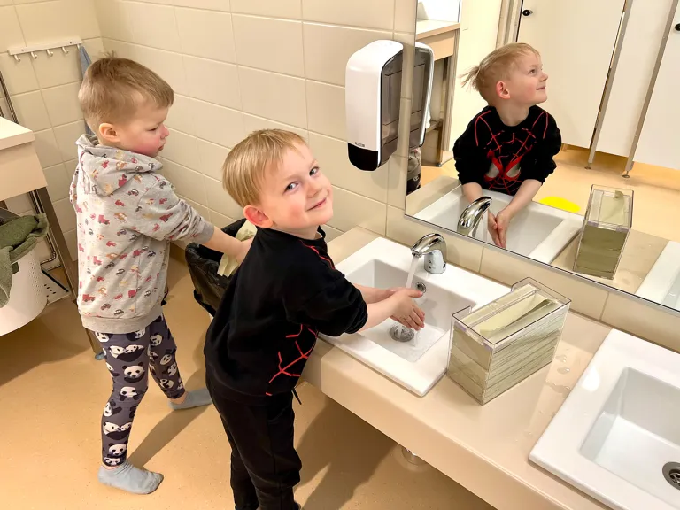 Lapset pesemässä käsiään lavuaarin yllä.